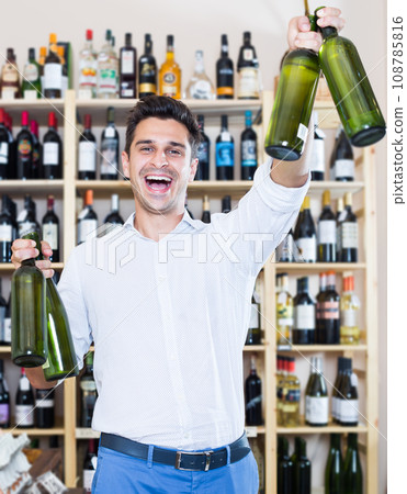 Smiling man holding wine bottles in winery section Smiling man holding wine bottles in winery section 108785816