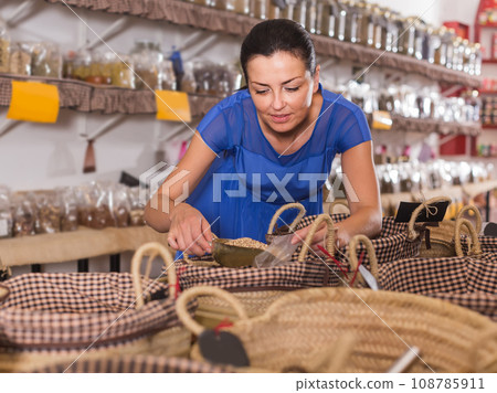 woman taking dried beans with shovel from backet in organic shop 108785911