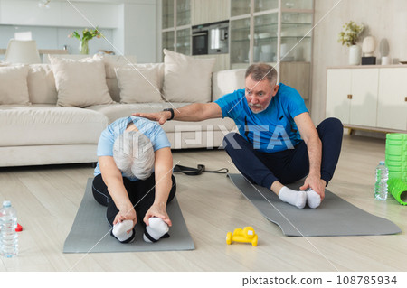Fitness workout training. Senior adult mature healthy fit couple doing sports exercise on yoga mat on floor at home. Mid age old husband wife have training workout. Health care healthy lifestyle Fitness workout training. Senior adult mature healthy fit couple doing sports exercise on yoga mat on floor at home. Mid age old husband wife have training workout. Health care healthy lifestyle 108785934