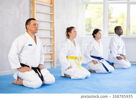 Middle-aged man judo practitioner in kimono sitting in seiza pose in sports hall Middle-aged man judo practitioner in kimono sitting in seiza pose in sports hall 108785935