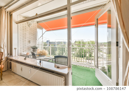 a living room with an orange awning on the window sie and green grass in the view is outside a living room with an orange awning on the window sie and green grass in the view is outside 108786147