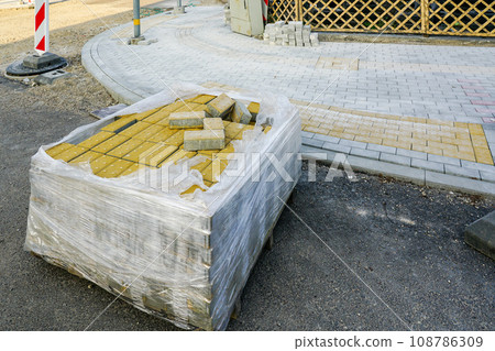 Street reconstruction view, pallet with yellow tactile paving stones for blind in foreground Street reconstruction view, pallet with yellow tactile paving stones for blind in foreground 108786309