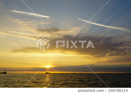 A beautiful multicolor golden sunset on the shore of the Baltic Sea, golden sunset on the seashore 108786324