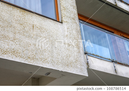 Defects in the facade of the building. Moss on the wall by the windows 108786514