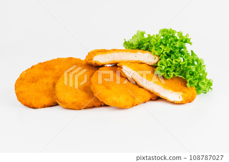 Breaded Chicken Inner Fillet with green lettuce leaves on a White Background,Chicken Breaded Raw Meat,Fillet.Breaded chicken nuggets. Fast homemade food at home.Chicken breaded schnitzels.Fast cooking 108787027