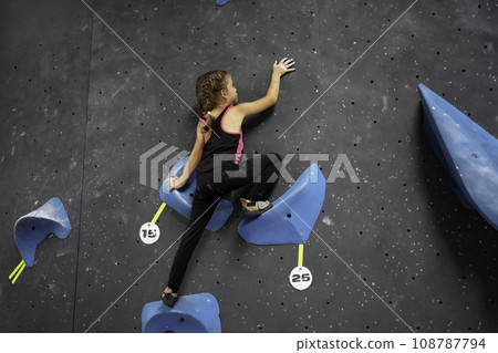 Little girl in sportswear is climbing wall entertainment center 108787794