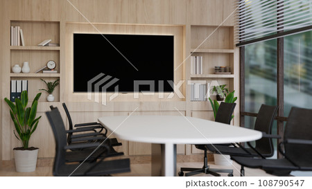 A modern, minimalist meeting room with a meeting table and a TV screen on the wood wall. A modern, minimalist meeting room with a meeting table and a TV screen on the wood wall. 108790547