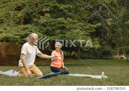 Senior man and woman with yoga mats standing at park. Positive mature man and his elderly wife have a fitness or yoga class in nature. Wellness and healthy lifestyle on retirement. Senior man and woman with yoga mats standing at park. Positive mature man and his elderly wife have a fitness or yoga class in nature. Wellness and healthy lifestyle on retirement. 108790591