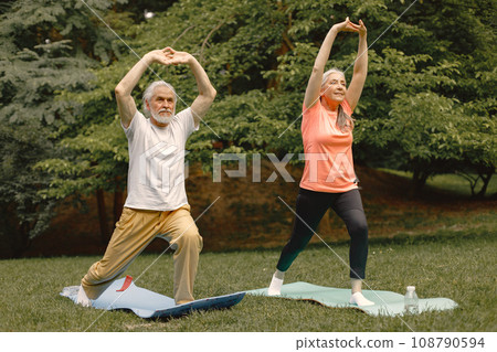 Senior man and woman with yoga mats standing at park. Positive mature man and his elderly wife have a fitness or yoga class in nature. Wellness and healthy lifestyle on retirement. Senior man and woman with yoga mats standing at park. Positive mature man and his elderly wife have a fitness or yoga class in nature. Wellness and healthy lifestyle on retirement. 108790594