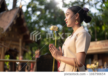 A beautiful Asian woman in a traditional Thai-Lanna dress is making a wish in a temple. Thai culture A beautiful Asian woman in a traditional Thai-Lanna dress is making a wish in a temple. Thai culture 108790654