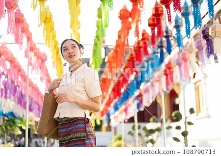 A beautiful Asian-Thai woman in a traditional dress is enjoying in a lantern festival at a temple. A beautiful Asian-Thai woman in a traditional dress is enjoying in a lantern festival at a temple. 108790713