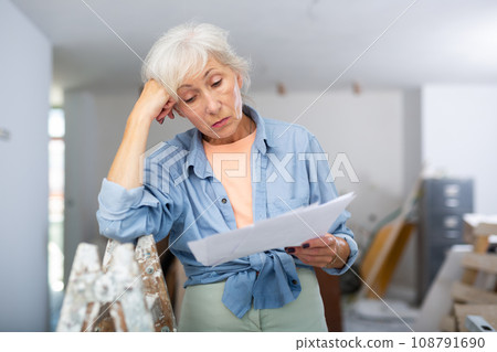 Stressed woman with papers in renovating house Stressed woman with papers in renovating house 108791690