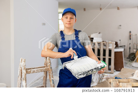 Portrait of teenage boy with paint roller in building site 108791913