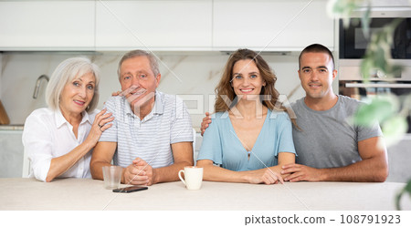 Portrait of a happy family of four sitting together at kitchen table 108791923