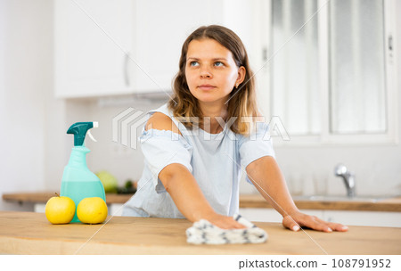 Positive woman cleaning kitchen table at home Positive woman cleaning kitchen table at home 108791952