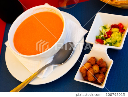 Cold gazpacho soup in a bowl, served with baked bread and vegetables 108792015
