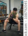 lifting a dumbbell to work the muscles in his bicep. 108792045