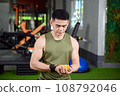 A man sits and adjusts his wrist brace. 108792046