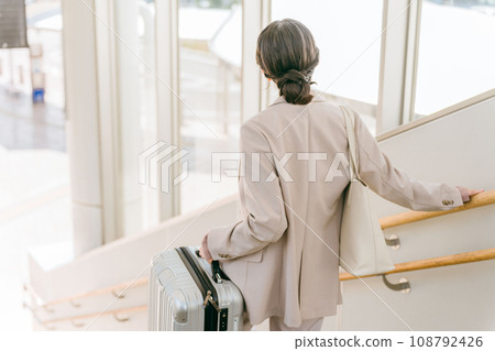 A woman carrying heavy luggage on the stairs (station/airport) A woman carrying heavy luggage on the stairs (station/airport) 108792426