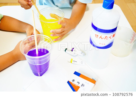 Transparent purple and yellow slime made by children using borax, laundry starch, and paint on a white desk. Transparent purple and yellow slime made by children using borax, laundry starch, and paint on a white desk. 108792576