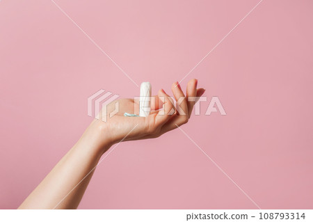 Tampon in female hand on a pink background. copy space Tampon in female hand on a pink background. copy space 108793314