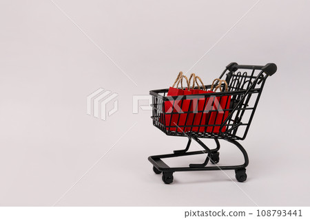 Black shopping cart with red paper bags on gray background, copy space. black friday concept Black shopping cart with red paper bags on gray background, copy space. black friday concept 108793441