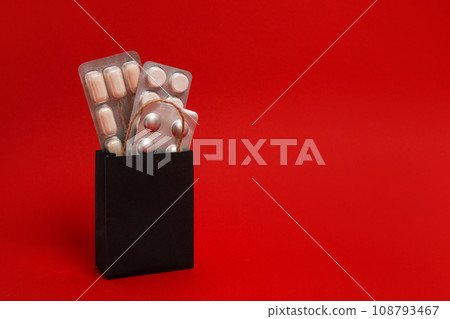 Pills, medical products in black paper bag on red background. Copy space, black friday sale in pharmacy 108793467