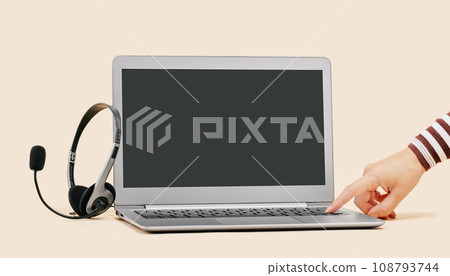 Front view of slim laptop with headset on beige. Female hand turning on. Distant learning. working from home, online courses or support. Audio podcast headphones . Helpdesk or call center banner 108793744
