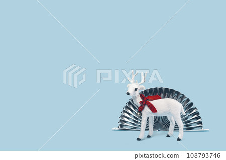 White toy reindeer on Christmas blue background. Merry Christmas and Happy New Year seasons greetings concept. Edgeless centered minimal. White toy reindeer on Christmas blue background. Merry Christmas and Happy New Year seasons greetings concept. Edgeless centered minimal. 108793746