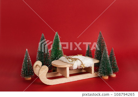 eco Natural wooden toy sled with Christmas trees on red background.New Year podium for your products eco Natural wooden toy sled with Christmas trees on red background.New Year podium for your products 108794265