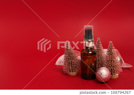 Cosmetic brown glass serum bottle with Christmas pink decorations. red background with copy space 108794267