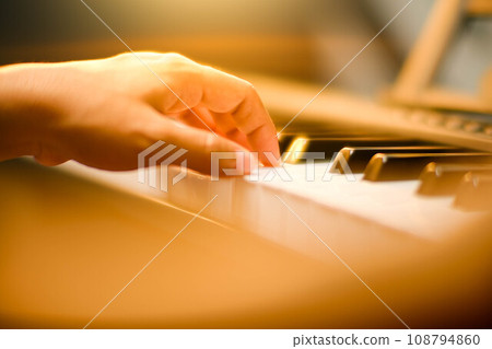 Close-up of a little student's hand playing the piano. Happy young Asian girl learning and practicing the piano. Selective focus. Close-up of a little student's hand playing the piano. Happy young Asian girl learning and practicing the piano. Selective focus. 108794860