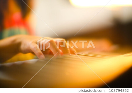 Close-up of a little student's hand playing the piano. Happy young Asian girl learning and practicing the piano. Selective focus. Close-up of a little student's hand playing the piano. Happy young Asian girl learning and practicing the piano. Selective focus. 108794862