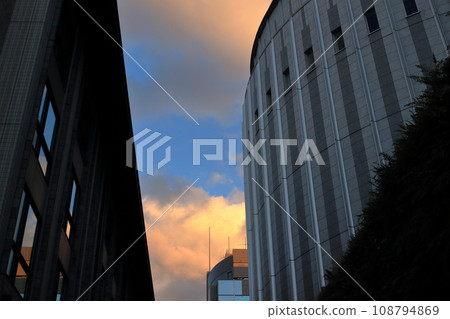 日落時在建築物之間看到的雲 108794869