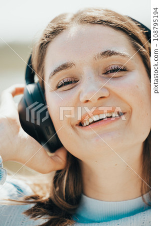 Beach Beats: Sunlit Tourist Enjoys Music by the Sea 108795194