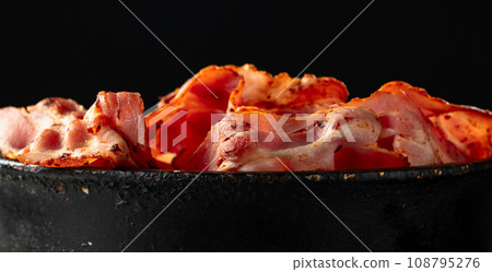 Fried bacon slices in old black pan. Fried bacon slices in old black pan. 108795276