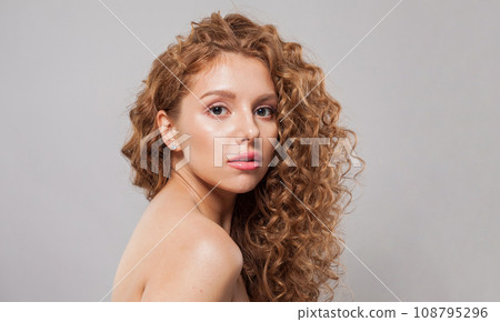 Attractive woman with wavy hair and natural makeup. Young fashion model with long curly hairstyle Attractive woman with wavy hair and natural makeup. Young fashion model with long curly hairstyle 108795296