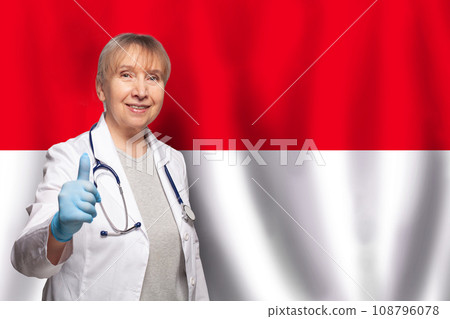 Indinezian smiling mature doctor woman holding stethoscope on flag of Indinezian background Indinezian smiling mature doctor woman holding stethoscope on flag of Indinezian background 108796078