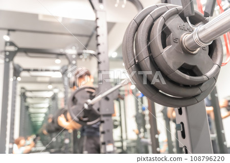A man setting up a barbell at a training gym 108796220