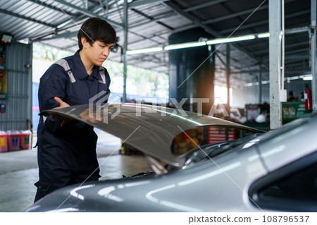 Team of vehicle technicians checking and measuring a vehicle oil engine or engine lubricant level by using oil stick indicator. Senior professional repairman inspecting an oil engine in an old car. 108796537