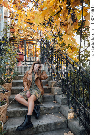 Beautiful woman sitting on steps with autumn leaves 108796613