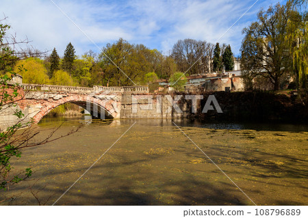 Old arched brick bridge across a pond in Sharovka Palace park in in Kharkov region, Ukraine 108796889