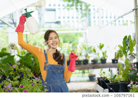Happy Asian woman doing a gardening and taking care small plants. Female gardener watering a cactus and house plant. Happy Asian woman doing a gardening and taking care small plants. Female gardener watering a cactus and house plant. 108797161