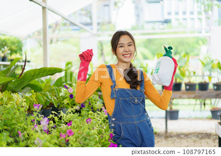 Happy Asian woman doing a gardening and taking care small plants. Female gardener watering a cactus and house plant. 108797165
