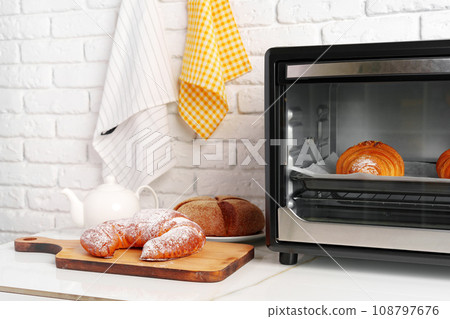 Modern mini electric oven with freshly baked croissants in kitchen 108797676