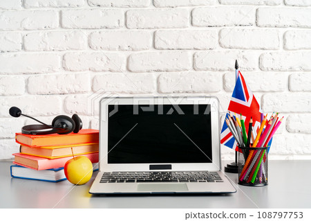 Laptop and flag of UK on desk. English language learning concept Laptop and flag of UK on desk. English language learning concept 108797753