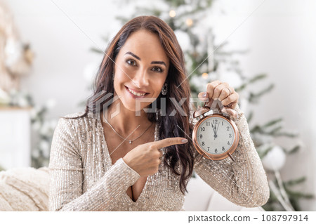 Woman pointing at the clock showing that Christmas is just around the corner Woman pointing at the clock showing that Christmas is just around the corner 108797914