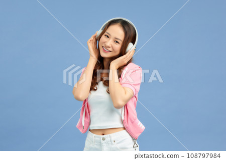 Happy beautiful Asian woman listening music in headphones and dance on color background. Happy beautiful Asian woman listening music in headphones and dance on color background. 108797984
