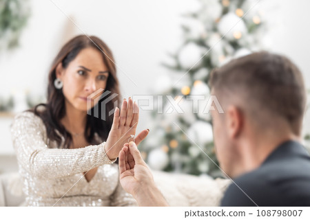 Woman declines a proposal to a man kneeing in front of her with a ring in his hand during Christmas Woman declines a proposal to a man kneeing in front of her with a ring in his hand during Christmas 108798007