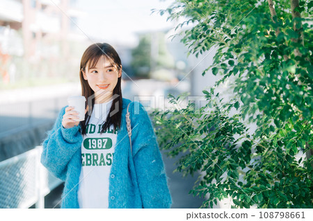 A woman strolling around town while holding coffee 108798661
